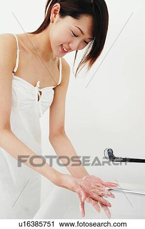 Stock Image - Woman washing her hands in the restroom. Fotosearch