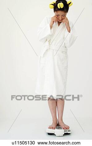 Stock Image - Woman weighing herself on the scales. Fotosearch