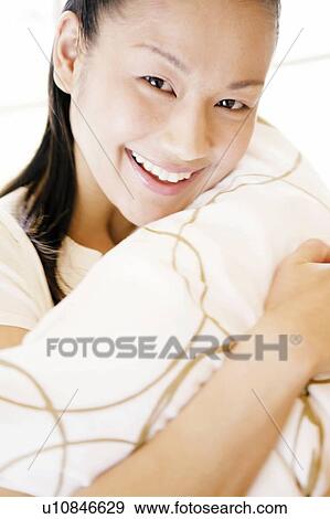 Stock Photo - Young Woman Looking at Camera and Holding Pillow. Fotosearch
