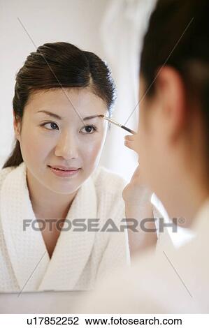 Stock Image - Young Woman Making Up In Front Of The Mirror. Fotosearch