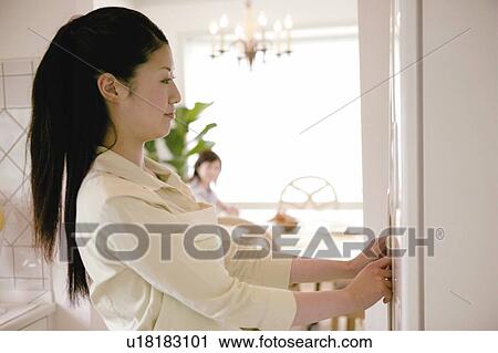 Stock Image - Young Woman Opening Refrigerator's Door. Fotosearch