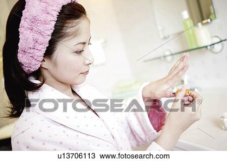Stock Image - Young Woman Painting On Fingernail. Fotosearch