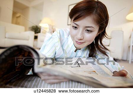 Stock Photo - Young Woman Reading Magazine and Lying Down. Fotosearch