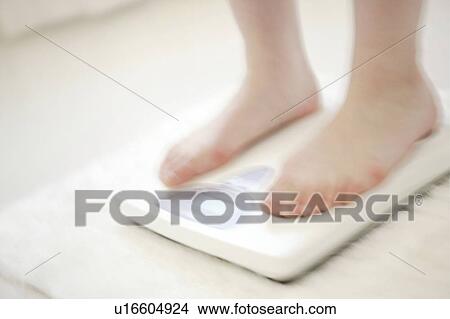 Picture - Young Woman Standing On Bathroom Scale. Fotosearch