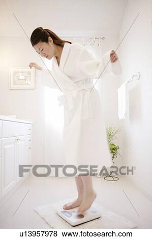 Stock Photo - Young Woman Standing On Bathroom Scale. Fotosearch