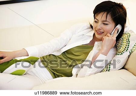 Stock Photo - Young Woman Talking On Mobile Phone and Lying Down. Fotosearch