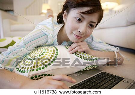 Stock Photo - Young Woman Using Computer and Lying Down. Fotosearch