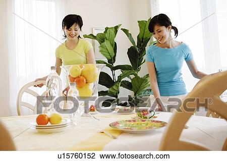 Stock Image - Young Women In Dining Room. Fotosearch