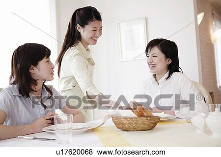 Stock Photo - Young Women Putting Basket On Table. Fotosearch
