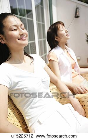 Stock Image - Young Women Relaxing At Porch. Fotosearch