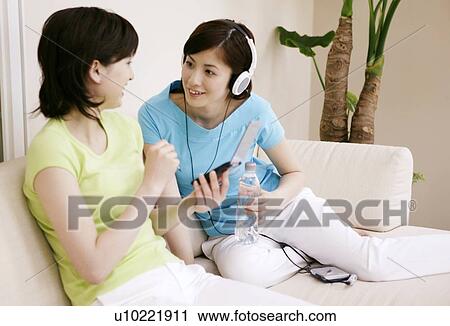 Stock Image - Young Women Using PDA and Listening Music. Fotosearch