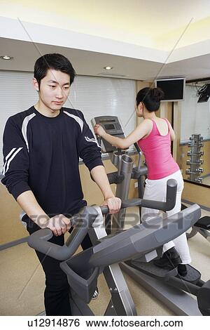 Stock Photograph - Close-up of a young man and a young woman exercising in a gym. Fotosearch