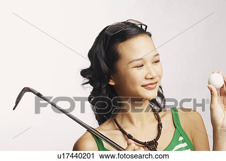 Stock Image - Close-up of a young woman holding a golf club and a golf ball. Fotosearch