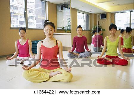 Stock Image - Four young women sitting in the lotus position. Fotosearch
