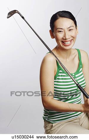 Picture - Portrait of a mid adult woman holding a golf club and smiling. Fotosearch