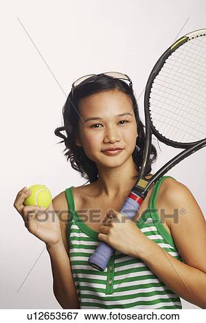 Portrait of a young woman holding a tennis racket and a tennis ball View Large Photo Image Stock Photo - Portrait of a young woman holding a tennis racket and a tennis ball. Fotosearch