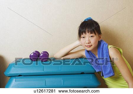 Stock Image - Portrait of a young woman leaning on a stack of aerobic steps. Fotosearch