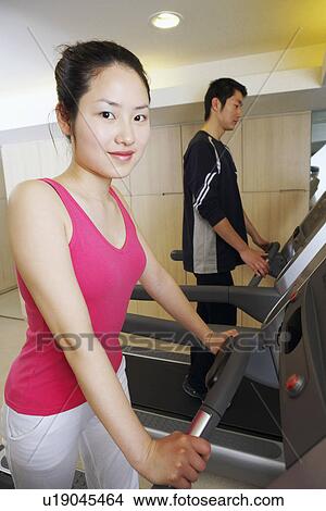 Side profile of a young woman and a young man exercising in a gym View Large Photo Image Picture - Side profile of a young woman and a young man exercising in a gym. Fotosearch