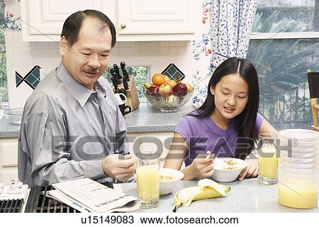 Stock Image - Close-up of a father and his daughter in the kitchen. Fotosearch