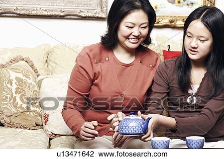 Close-up of a girl holding a teapot sitting with her mother View Large Photo Image Stock Image - Close-up of a girl holding a teapot sitting with her mother. Fotosearch