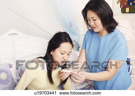 Stock Image - Close-up of a mother checking her daughter's temperature. Fotosearch