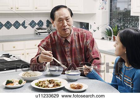 Stock Photo - Grandfather and his granddaughter sitting at a table. Fotosearch
