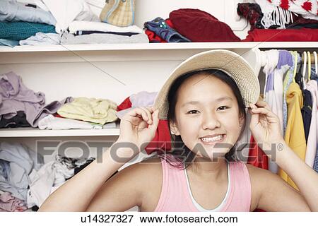 Stock Photo - Portrait of a girl holding a hat on her head. Fotosearch