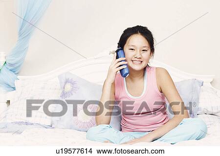 Picture - Portrait of a girl using a cordless telephone. Fotosearch