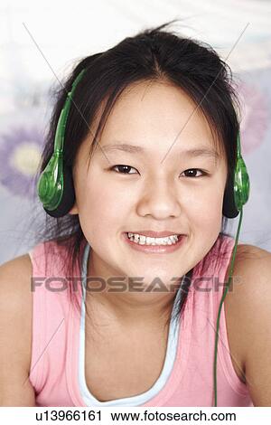 Stock Image - Portrait of a girl wearing headphones listening to music. Fotosearch