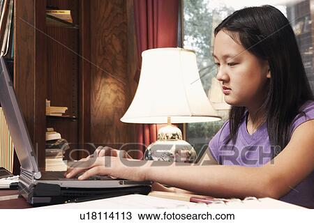 Stock Image - Side profile of a girl using a laptop. Fotosearch