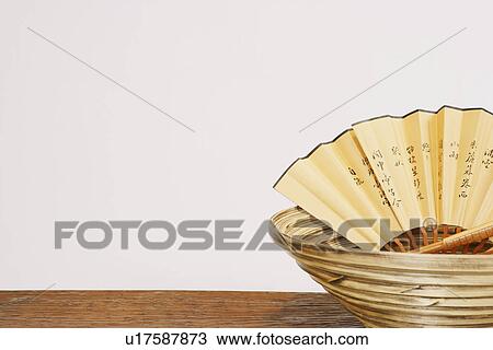 Stock Image - Close-up of a folding fan in a basket. Fotosearch