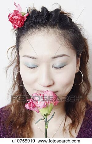 Stock Photo - Close-up of a young woman smelling a flower. Fotosearch