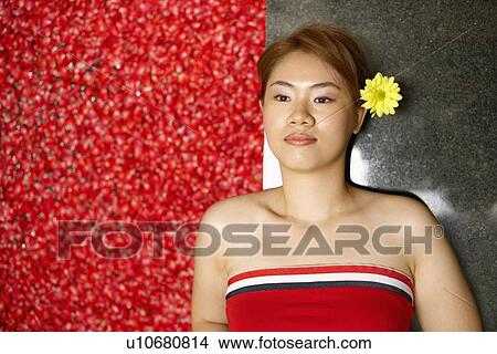 Picture - High angle view of a young woman lying on the floor near a hot tub filled with rose petals. Fotosearch