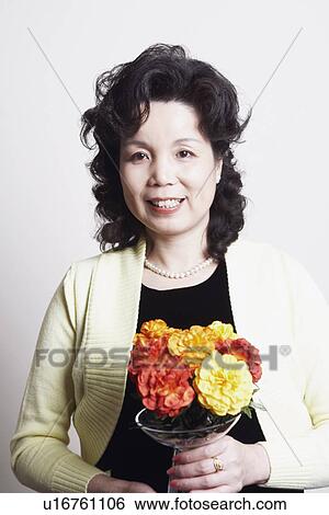 Stock Photograph - Portrait of a businesswoman holding a flower vase. Fotosearch