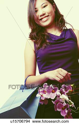 Picture - Portrait of a young woman carrying flowers with shopping bags and smiling. Fotosearch