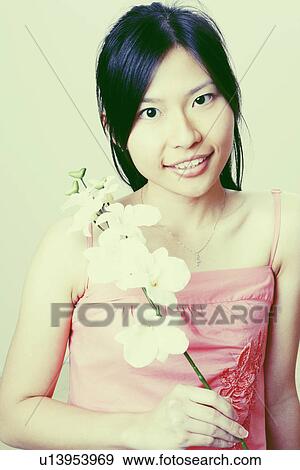 Portrait of a young woman holding a flower and smiling View Large Photo Image Stock Photo - Portrait of a young woman holding a flower and smiling. Fotosearch