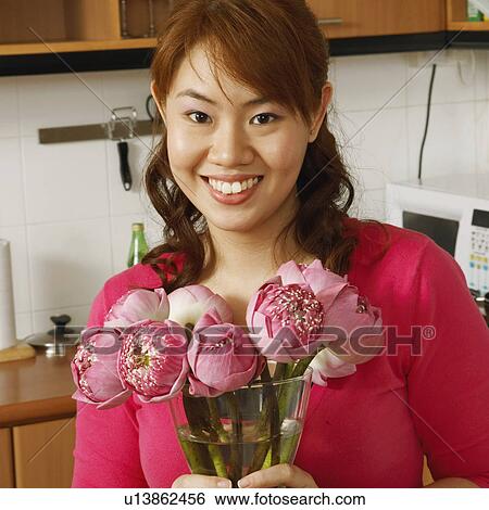 Portrait of a young woman holding a flower vase in the kitchen View Large Photo Image Stock Photograph - Portrait of a young woman holding a flower vase in the kitchen. Fotosearch
