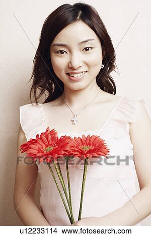 Portrait of a young woman holding flowers View Large Photo Image Picture - Portrait of a young woman holding flowers. Fotosearch