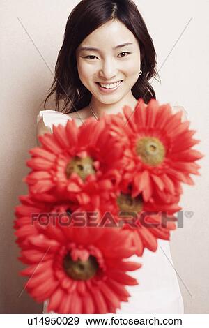 Portrait of a young woman holding flowers View Large Photo Image Stock Photo - Portrait of a young woman holding flowers. Fotosearch