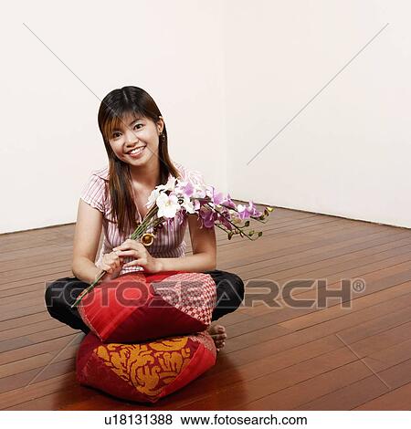 Portrait of a young woman holding flowers on the floor and smiling View Large Photo Image Stock Photo - Portrait of a young woman holding flowers on the floor and smiling. Fotosearch