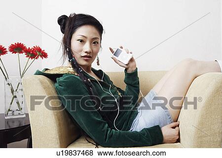 Stock Photo - Portrait of a young woman listening to music. Fotosearch