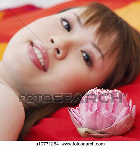 Picture - Portrait of a young woman lying on the bed and smiling. Fotosearch