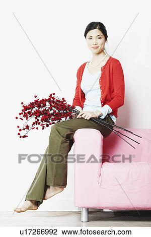 Portrait of a young woman sitting on the arm of an arm chair View Large Photo Image Stock Image - Portrait of a young woman sitting on the arm of an arm chair. Fotosearch
