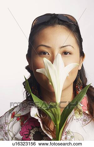 Portrait of a young woman smelling a flower View Large Photo Image Stock Photograph - Portrait of a young woman smelling a flower. Fotosearch