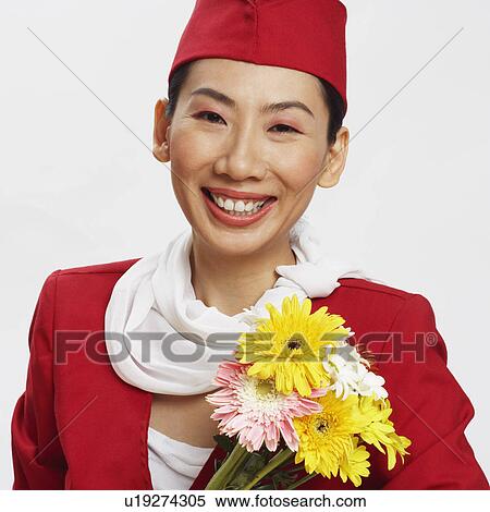 Stock Photography - Portrait of an air stewardess holding flowers and smiling. Fotosearch