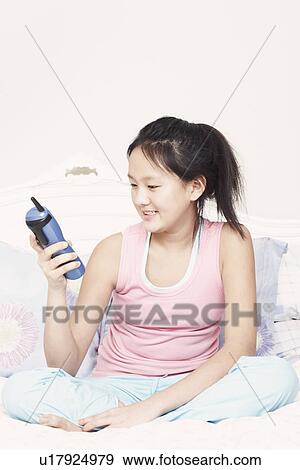 Stock Photo - Close-up of a girl holding a cordless telephone. Fotosearch