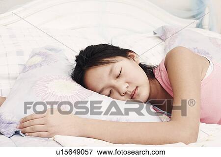 Stock Photo - Girl lying on the bed with her eyes closed. Fotosearch