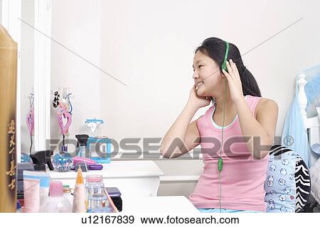 Stock Photo - Girl wearing headphones listening to music. Fotosearch