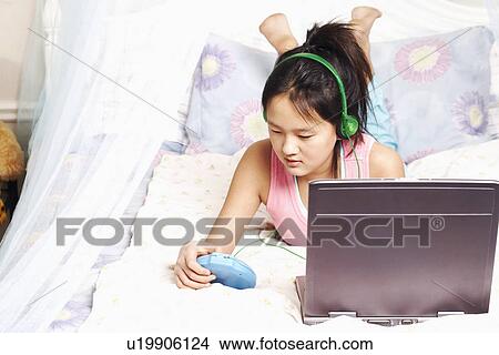 Picture - High angle view of a girl listening to music on an MP3 player. Fotosearch