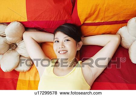 High angle view of a young woman smiling with her hands behind her head View Large Photo Image Stock Photo - High angle view of a young woman smiling with her hands behind her head. Fotosearch